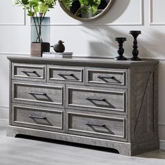 a wooden dresser sitting next to a wall with a mirror on it's side