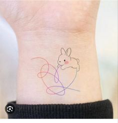 a small wrist tattoo with a bunny on it's left side and a heart in the middle