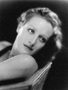 black and white photograph of a woman with her hand on the back of a chair