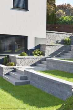 a modern house with stone steps leading up to the front door and landscaping area on both sides