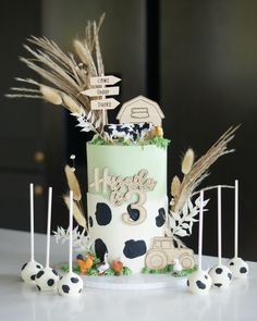 there is a cake decorated with farm animals and grass on the table next to it