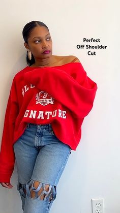 a woman leaning against a wall wearing ripped jeans and a red sweatshirt with the words, perfect off shoulder cut