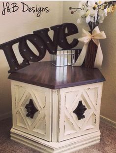 a love sign sitting on top of a white cabinet next to a vase with flowers