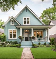 a blue house with white trim and windows on the front porch is surrounded by lush green grass