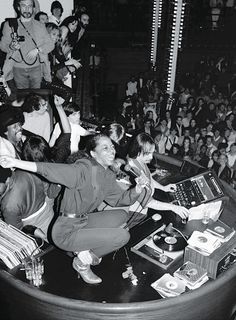 a woman sitting on top of a round table in front of a crowd