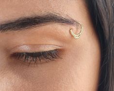 a close up of a person's eye with a gold nose ring on it