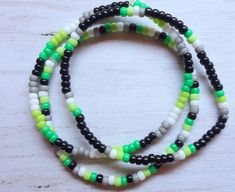 These skinny beaded bracelets are striking as minimalist pieces on their own or layered with each other or different bracelets. Size 8/0 Miyuki glass seed beads in ARO Pride flag colors are strung in a single line: Dark Green, Light Green, White, Gray and Black. Choose from three different designs (see numbered photo), or mix and match: 1 - BLACK BAND - Primary color is black, with single sets of four beads sprinkled around the bracelet in dark green, light green, white and gray. 2 - DASHES - Fl Aro Pride, Pride Bracelets, Bracelets Minimalist, Jewelry Stack, Stack Bracelets, Layering Jewelry, Pride Flag Colors, Pride Bracelet, Stretch Ring