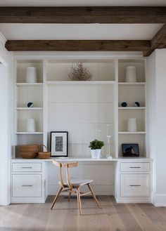 a white desk and chair in a room with wooden floors, built - in bookshelves and open shelving