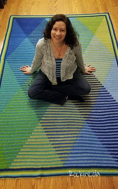 a woman sitting on top of a blue and green rug