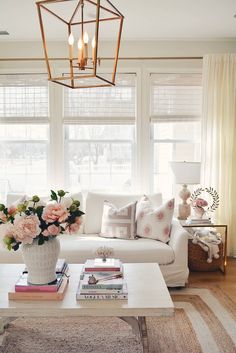 a living room filled with furniture and flowers in a vase on top of a coffee table