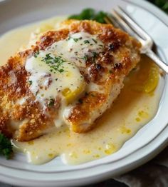 a white plate topped with chicken covered in sauce and parmesan cheese next to a fork