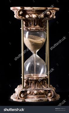 an old fashioned hourglass with sand running through it on a black backgroud