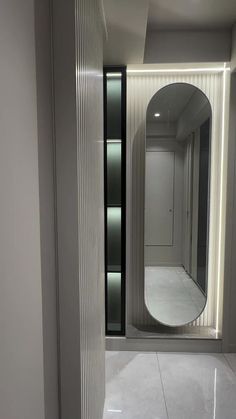 an empty room with a round mirror on the wall and white tile flooring in front of it