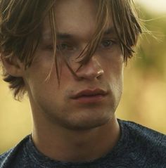 a close up of a man with long hair and blue eyes looking at the camera