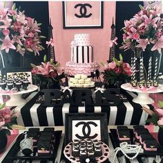 a chanel themed dessert table with pink flowers and black and white striped plates on it