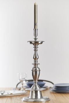 a metal candle holder sitting on top of a wooden table next to plates and glasses