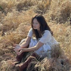 a woman sitting on the ground in tall grass