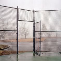 two gates open on a rainy day in front of a parking lot with no cars