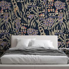 a bed with pillows and blankets in front of a wallpapered background that has flowers on it