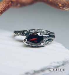 a close up of a ring with a red stone in it on a white surface