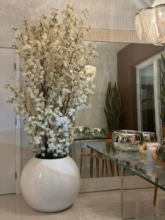 a vase filled with white flowers sitting on top of a table next to a mirror