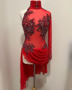 a red dress with silver beads on the neck and sleeves is displayed in front of a mannequin