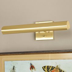 a gold light fixture mounted on the side of a wall next to a framed painting