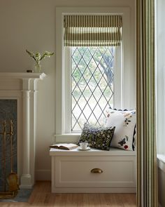 a window seat with pillows on it next to a fireplace