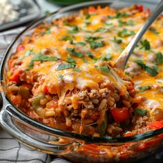 a glass casserole dish filled with ground beef and vegetables, topped with cheese