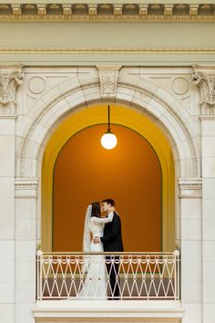 a bride and groom kissing on the balcony