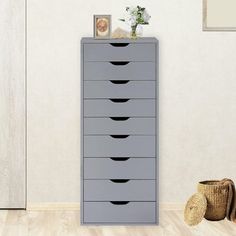 a tall gray dresser sitting on top of a hard wood floor next to a white wall