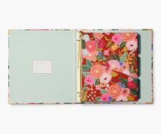 an open notebook with flowers and leaves on the cover, sitting on a white surface