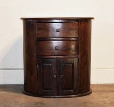 a wooden cabinet with two drawers on the bottom and one drawer at the top, in front of a white wall