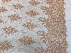 an embroidered fabric with gold flowers and leaves on white background, closeup view from the bottom