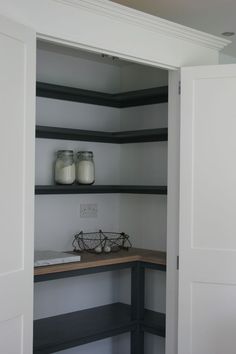 an open closet with shelves and jars on it