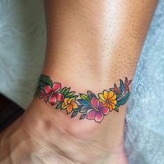 a woman's foot with flowers and leaves on the bottom part of her ankle