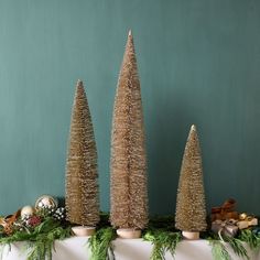 three small christmas trees sitting on top of a mantle