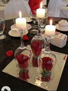 there are roses in vases with candles on the table