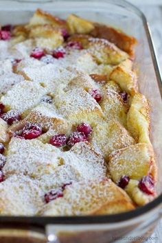 a casserole dish with powdered sugar and cranberries in it on a table