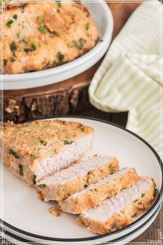 two white plates topped with slices of meat next to a casserole dish on a wooden table