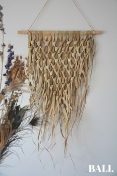 a wall hanging made out of rafters and sticks with dried flowers in the background