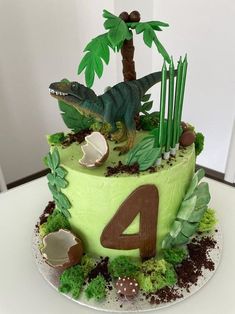 a dinosaur birthday cake with green frosting and decorations