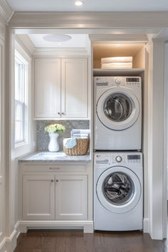 a washer and dryer in a white laundry room with wood flooring, built - in shelving, and cabinets