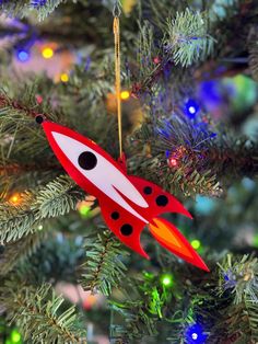 a red rocket ship ornament hanging from a christmas tree