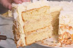 a person is holding a piece of cake with white frosting