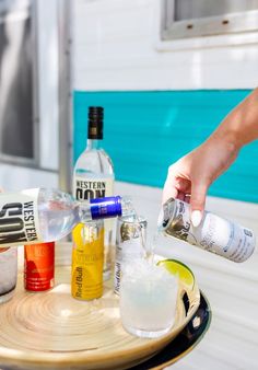 someone is pouring alcohol into a glass on a tray with liquor bottles and lemon wedges