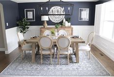 a dining room table with white chairs and a chandelier