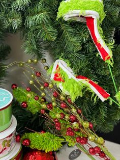 a green christmas tree with red and white ribbons hanging from it's branches next to a canister