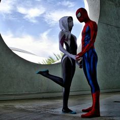 two spider - man standing next to each other in front of a round window with the sky behind them