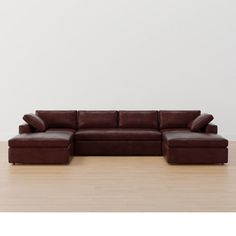 a brown leather couch sitting on top of a hard wood floor next to a white wall